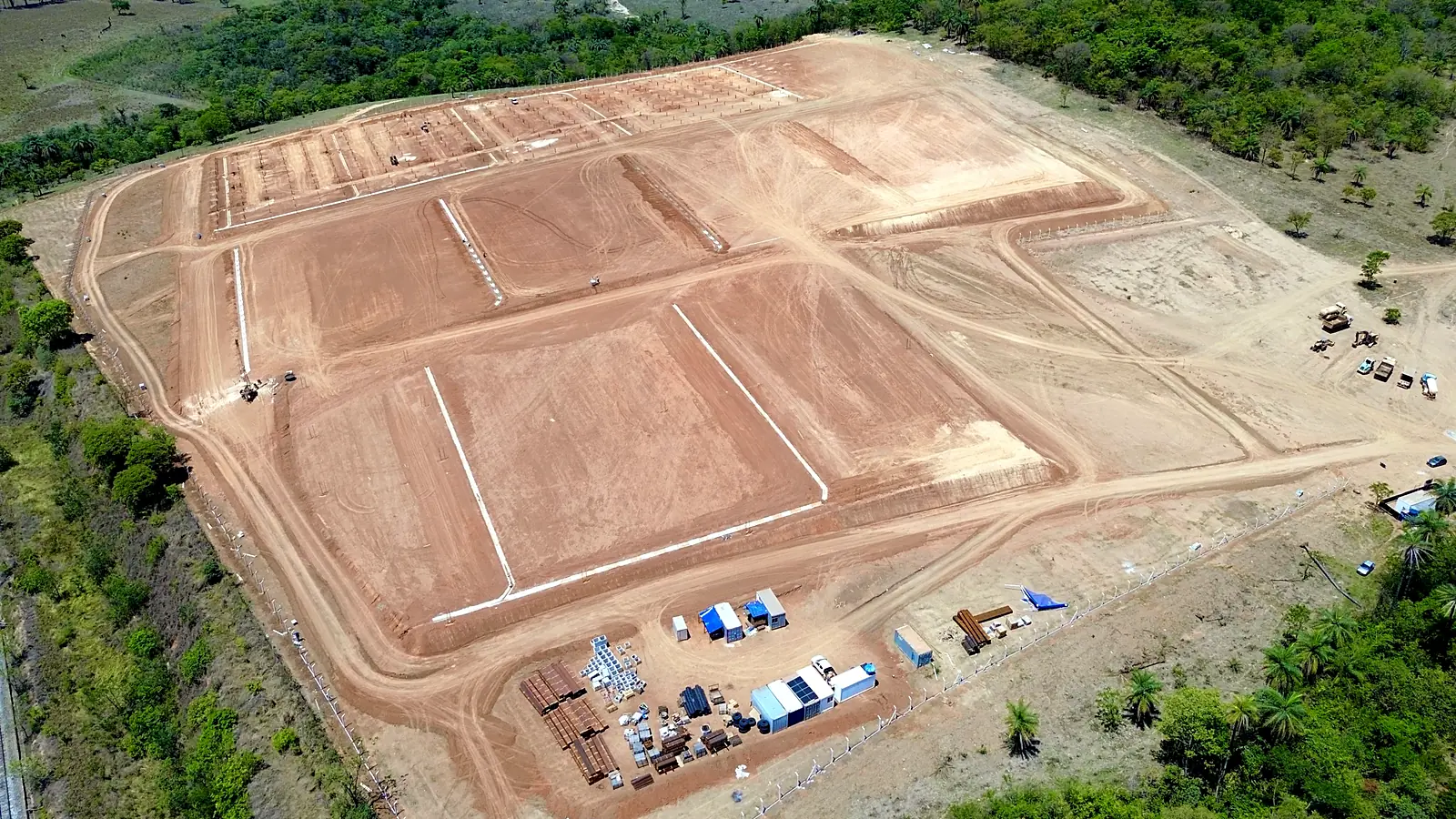 Depois: terreno terraplenado em plataformas, com acessos, cercamento e área de apoio da obra